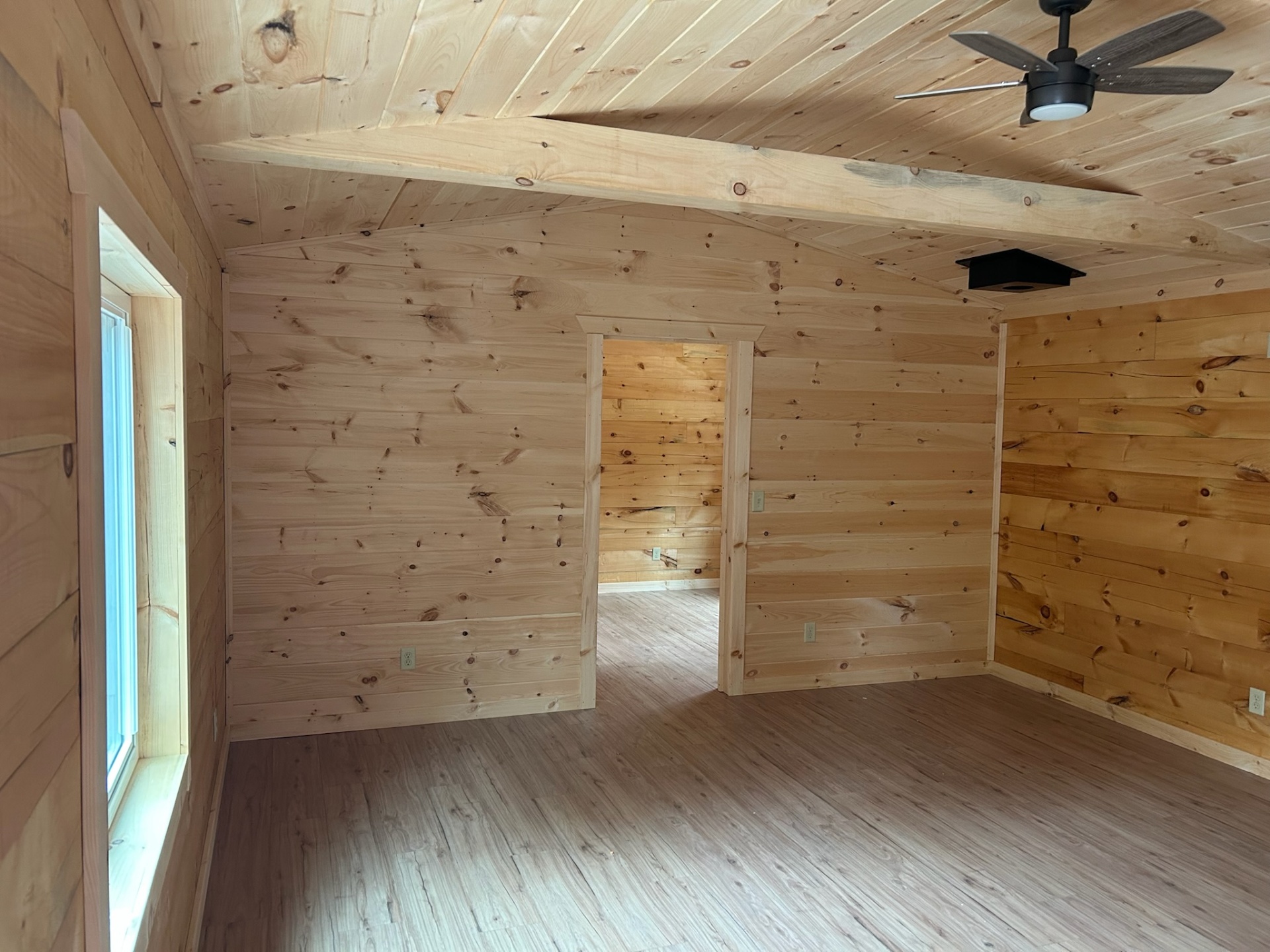 Open pine interior with bedroom doorway and ceiling fan