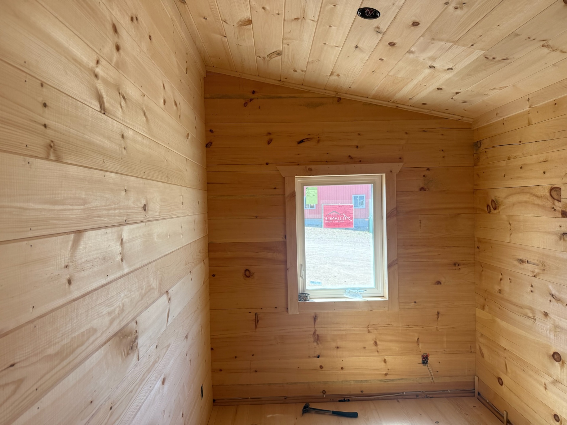 Bright pine interior corner with vaulted ceiling and window